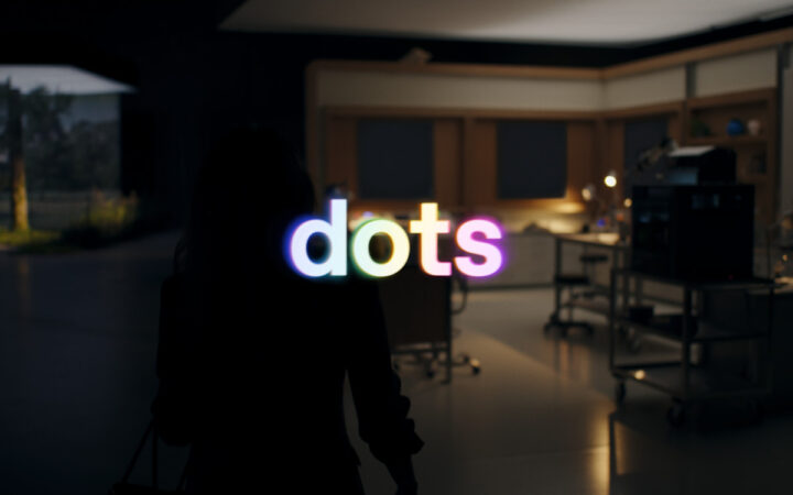 Colorful dots lettering over an office scene in OpenAI’s Dots introduction film