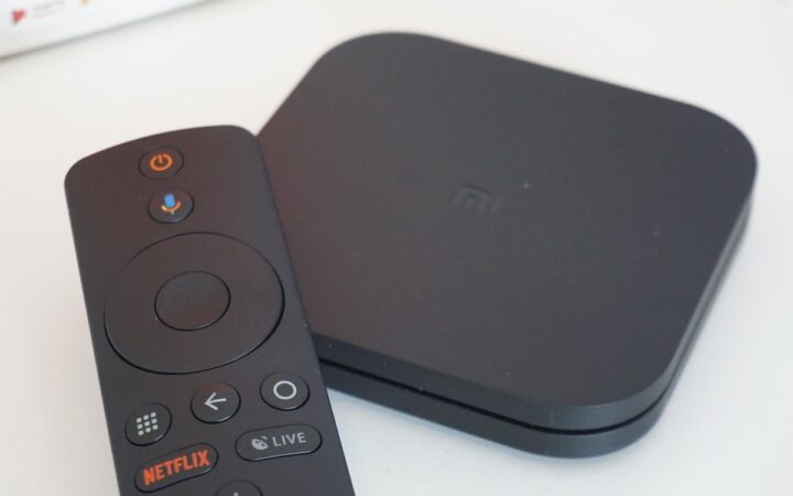 Xiaomi Mi Box S streaming device and remote on a light surface, used as an illustrative photograph