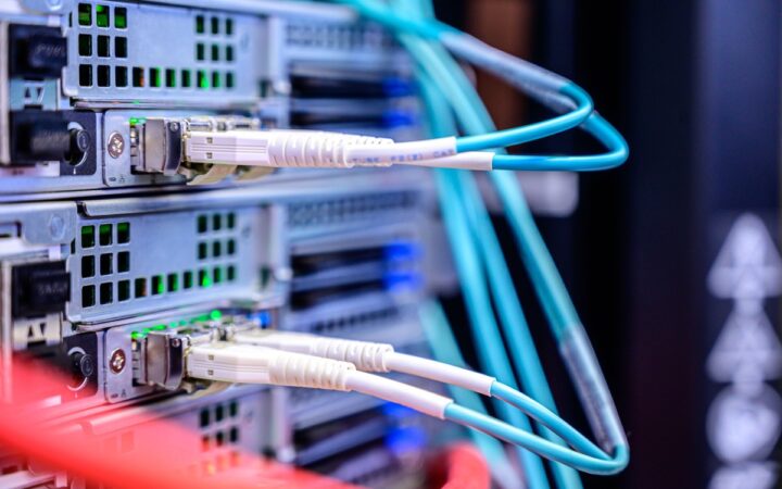 Close-up of server network ports with turquoise fiber optic cables and illuminated status lights